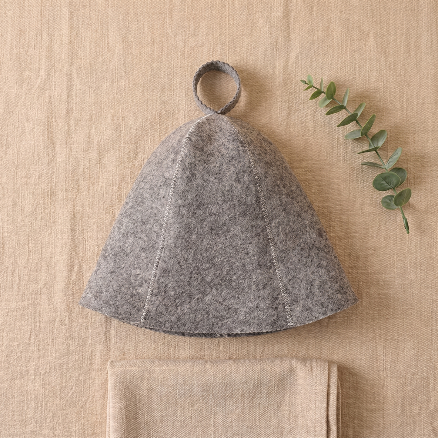 Flat lay of the Sawna sauna hat with eucalyptus and linen towel